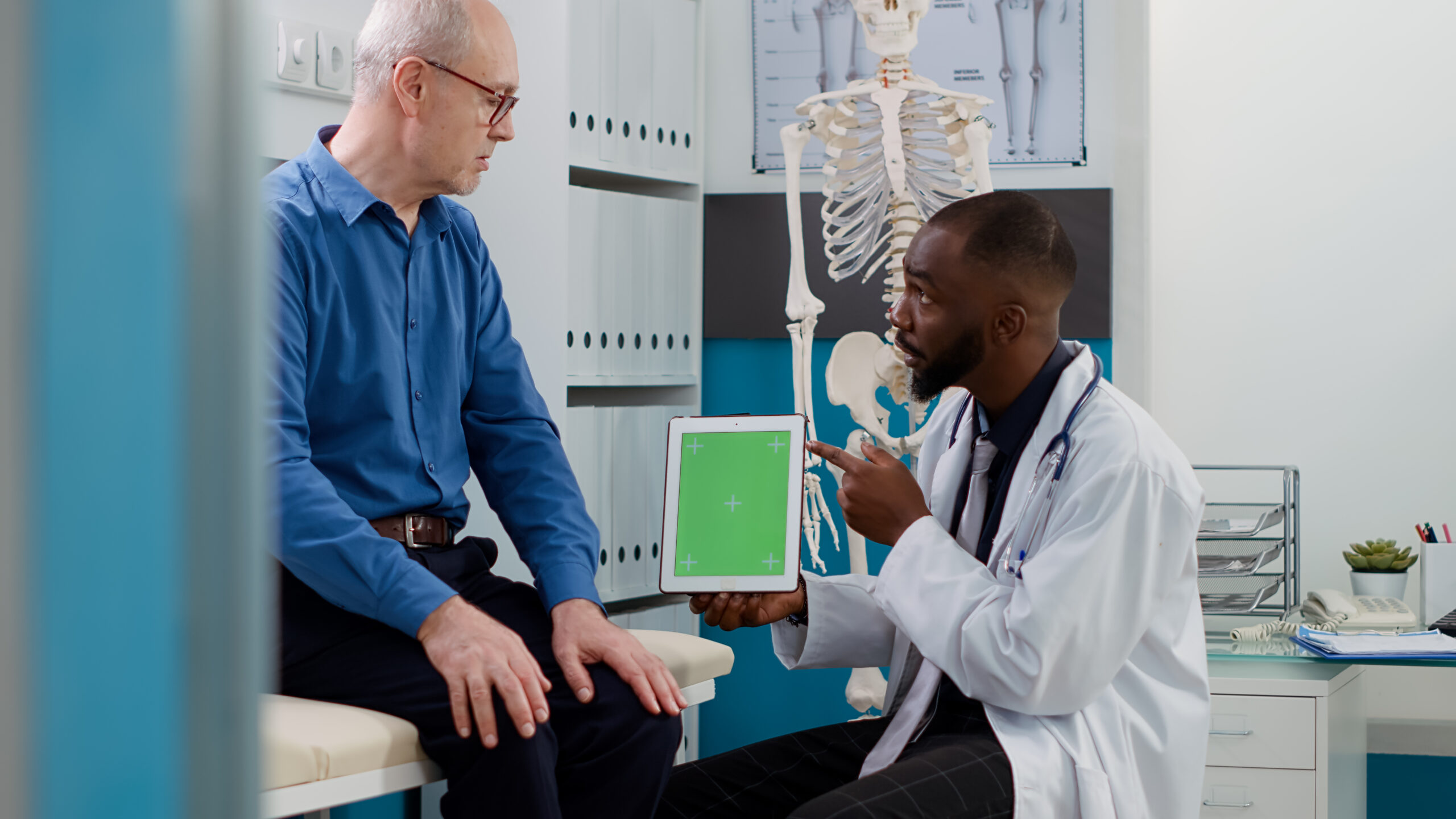 General practitioner holding greenscreen on tablet at checkup visit with male patient. Senior man and medic looking at blank copyspace display with chroma key background and isolated template.