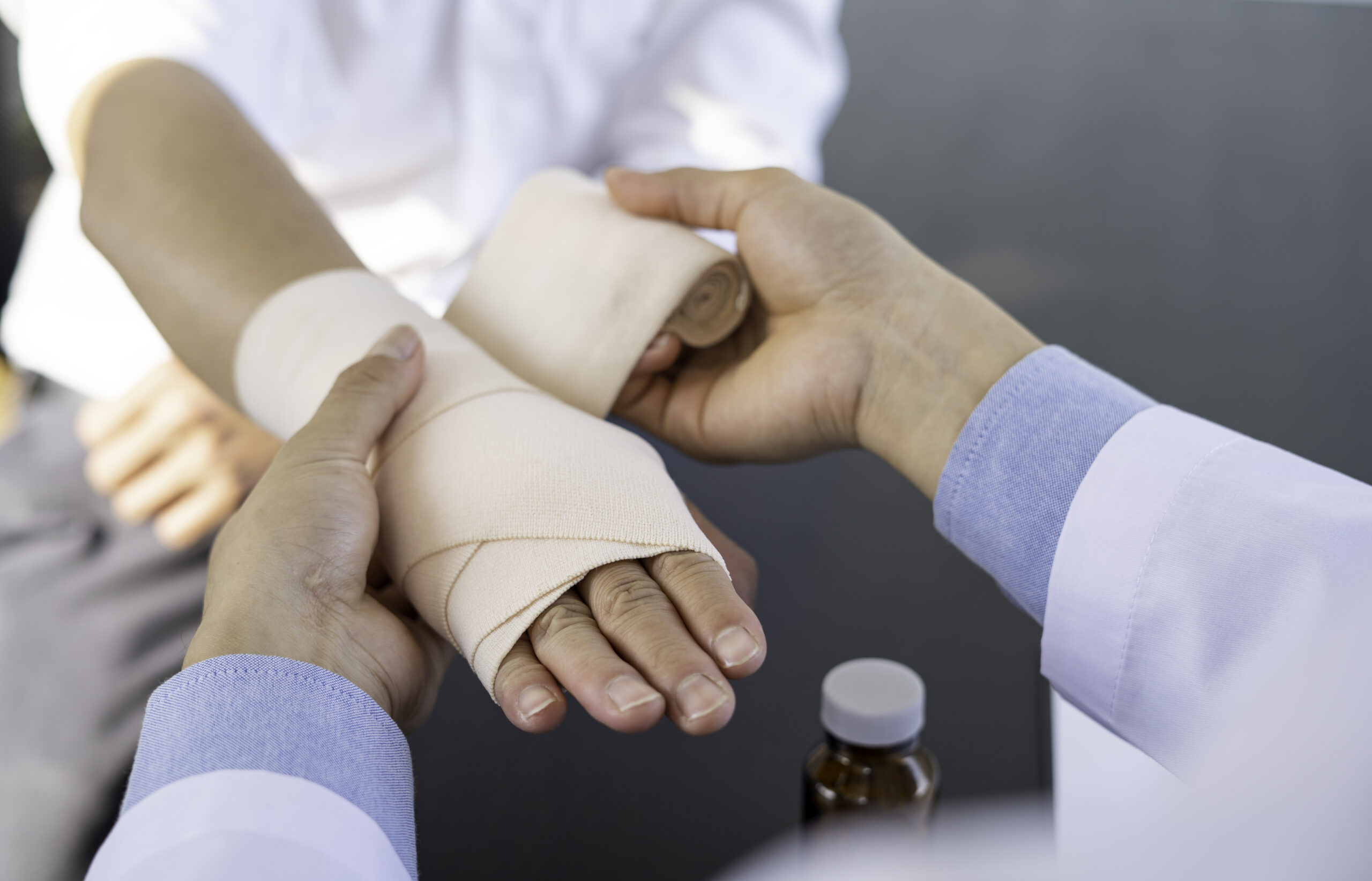 A doctor wrapped around the wrist for first aid Close-up with a particular emphasis on the application of bandages on the patient's hands, first aid concepts and wrist injury treatment.