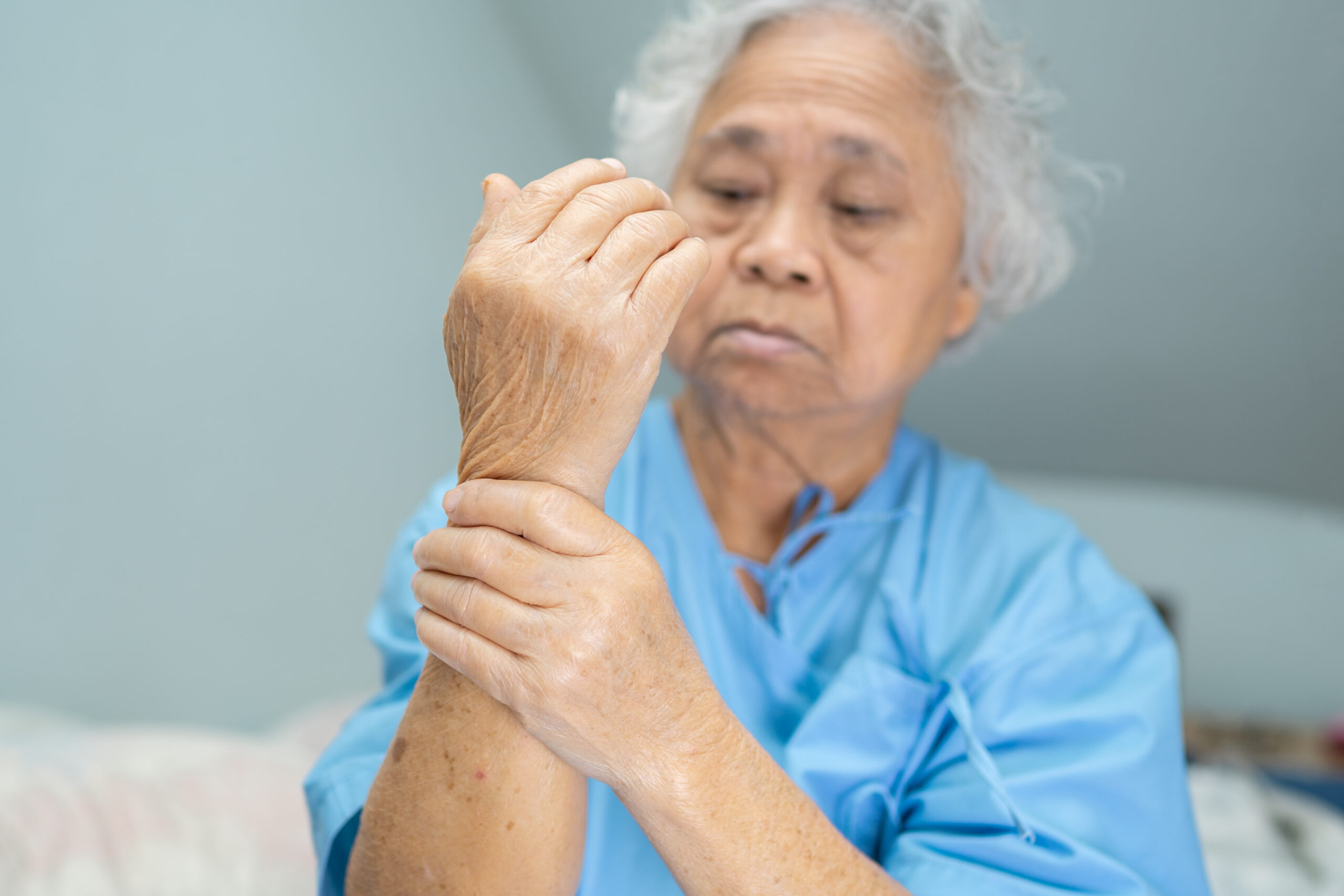 Asian senior or elderly old lady woman patient feel pain her hand on bed in nursing hospital ward, healthy strong medical concept.