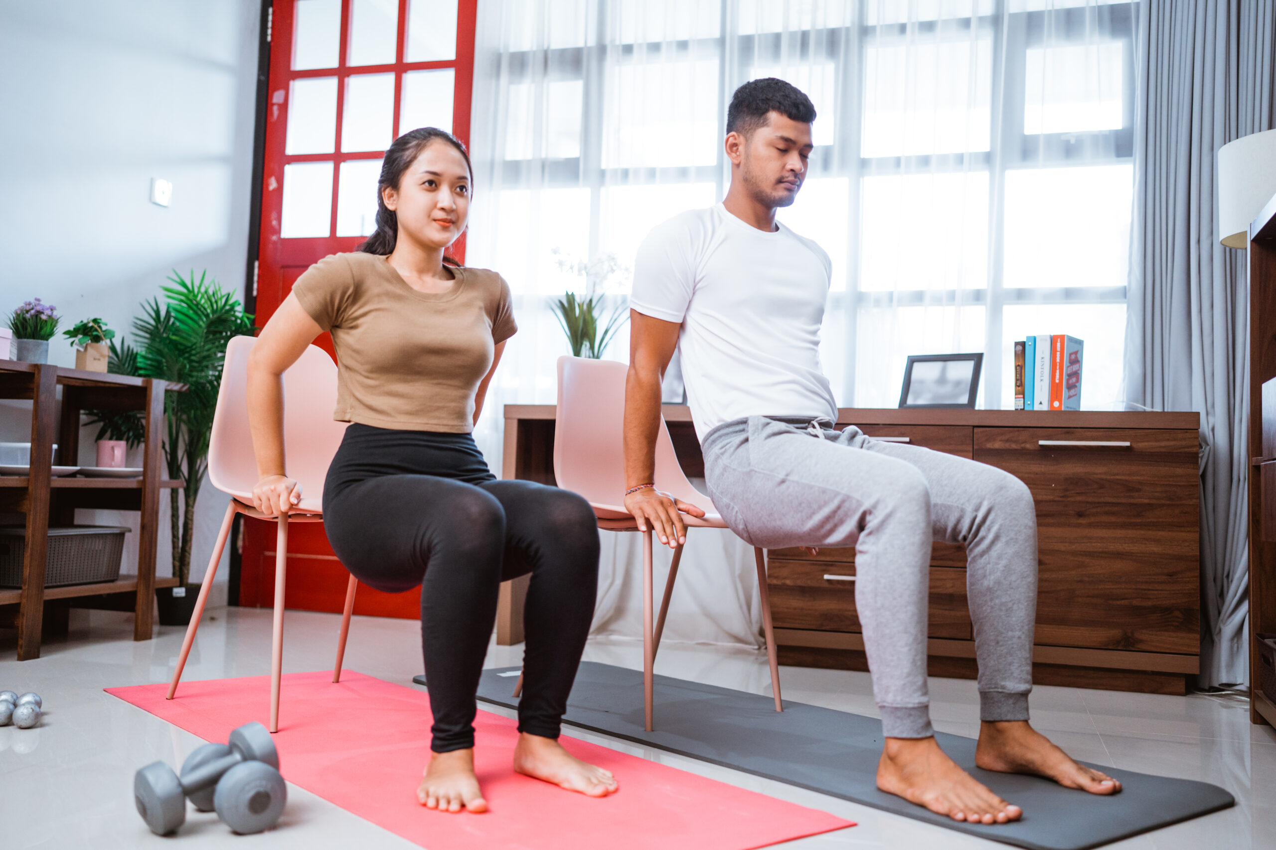 modern young asian couple exercising at home using chair to help them workout